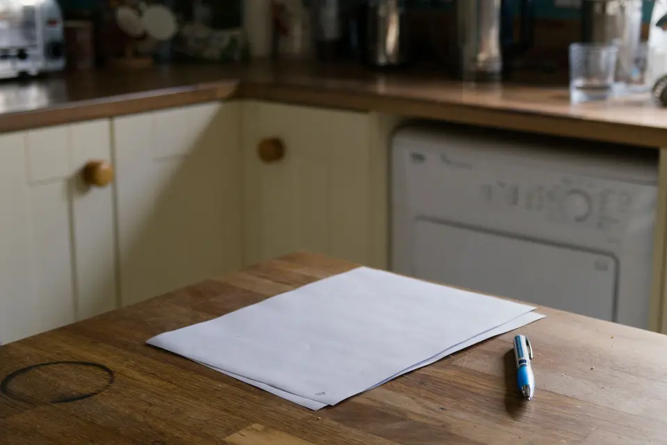Papieren en een pen op een houten keukentafel